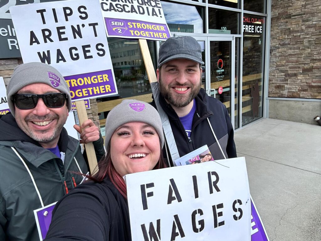 Three Cascadia workers on the picket line with picket signs.