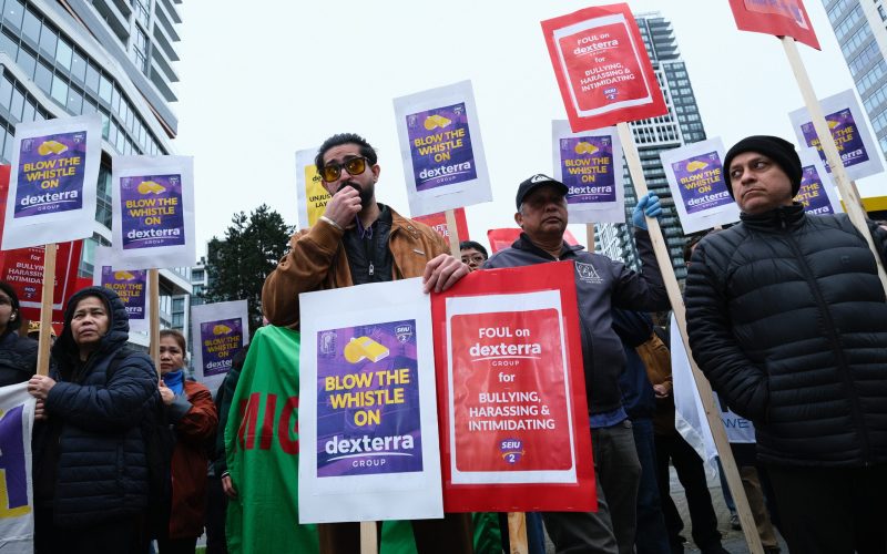 Sanchit Sharma, SEIU Member and Skytrain worker since 2023 stands in front of workers and blows a whistle.